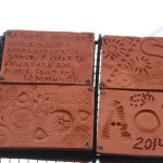 Clay tiles bordering the public art panel feature slogans praising Perry and its art festival.