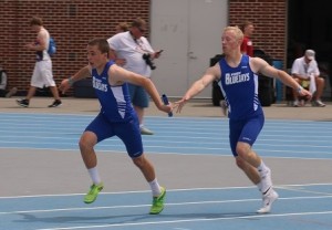 Perry freshman Reece Dunlap takes the baton from senior Nic Wilhelmi Friday in the 1600 medley at the state track meet.