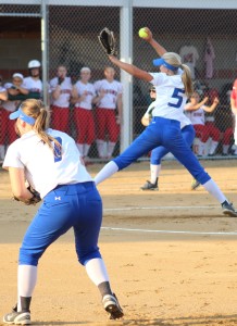 Emma Olejniczak pitches as first baseman Kate Whelchel (7) and third baseman Maddy Jans (rear) prepare to play defense.