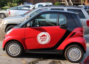 Two Mercedes Smart cars serve as the delivery fleet for the local Pizza Hut.