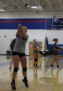Senior Ellie Nielsen returns the ball over the net during a hitting drill. Isabel Saemisch (at basket) and Gabby West (right) were also involved in the rotation.