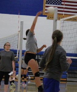Assistant coach Ali Tibbles (left) and head coach Kristel Schultz (right) look on as senior Taylor Lathrum swings for a kill.