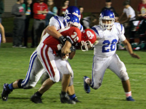 Toreador tailback Kaden Sherrard protects the ball as he is pulled down by Bluejay defensive tackle Tyler Soll as linebacker Mark Campos rushes in.