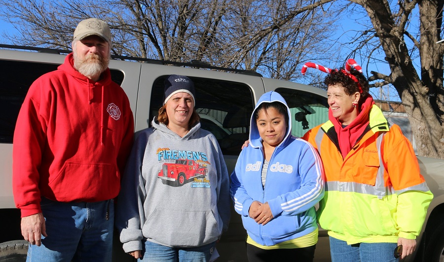 Josephina Nava of Perry, second from right, was happy for the holiday help delivered Friday morning by Perry Volunteer Fire Department members, from left, Grayson Hill, Aimee bane and Marion Lehman, who sported festive headwear.