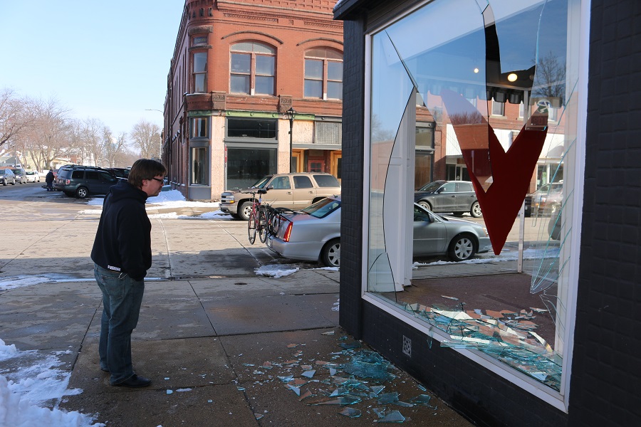Perry-Area Chamber of Commerce Executive Director Bob Wilson inspects the damage at 1121 Second St., the Betsy Peterson Design studio, where a plate glass window was broken.
