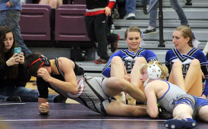 Perry's Zach Thompson scores a take down against Gilbert's Sinjin Briggs in their wrestle-back match at 120 pounds in the district tourney Saturday. Thompson won, 10-6, to return to the state tourney. Perry manager T.J. Sheehy snaps a photo of the action while cheerleaders Sadee Whitfield (left) and Chelsea Kroeger move clear of the action.