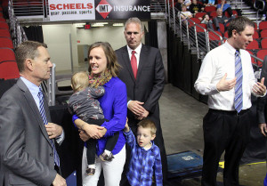 Scott Raeker (left) of Character Counts speaks with Meg Menke (holding daughter Brynn as son Pierce tries for her attention). Also present was Chuck Long of the Iowa Sports Foundation and, at right, Perry boys varsity basketball head coach Ned Menke.