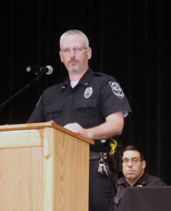 Perry Police School Resource Officer Pat Jans addresses the D.A.R.E. graduates as Detective Sergeant Jerome Hill listens Monday at the Perry Performing Arts Center.