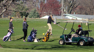Woodward-Granger's Paige Mescher blasts her tee shot down the second fairway at the Woodward Golf Club Monday. Among those watch are Hawk teammate Cierra DeHoet (far left).