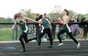 Anna Tague reaches back as Kayley Dresback closes in with the baton during the distance medley Tuesday.