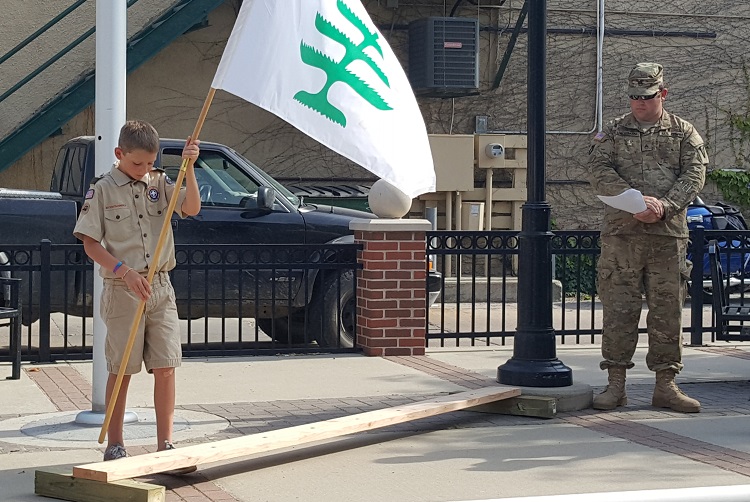 Jackson Tierney, left, of Boy Scout Troop 127 in Perry presents the Pine Tree Flag, flown during the American Revolution by colonial subjects in revolt against the British crown, while Perry Elk Chad Morman looks on during the Flag Day ceremony Saturday at Josh David Memorial Plaza in Perry.