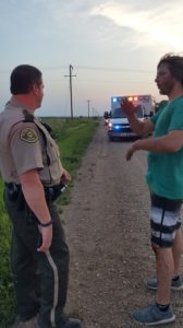 Boone County Deputy Sheriff Doug Twigg, left, interviews the son of the driver injured when his vehicle entered the ditch on a gravel road near Minburn. His son, smeared with his father's blood, described following in a second vehicle when the mishap occurred.