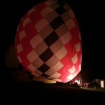The balloon crew inflated their balloon under darkness.