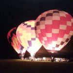 Three of the five dawn patrol balloons glow in the early morning hour.