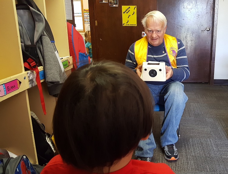 Perry Lions Clun member John Andorf smiles with encouragement at the youngsters at the Perry Child Development Center Thursday prior to giving the boy a quick and painless visions screening. The Perry Lions Club provides the free annual screenings to all Perry pre-schoolers.