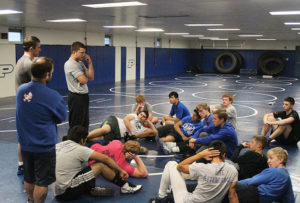 New Perry wrestling head coach Mark Weber from left) addresses the Bluejay matment Tuesday. Standing near are assistants Nick Field (near) and J.P. Hulgan.